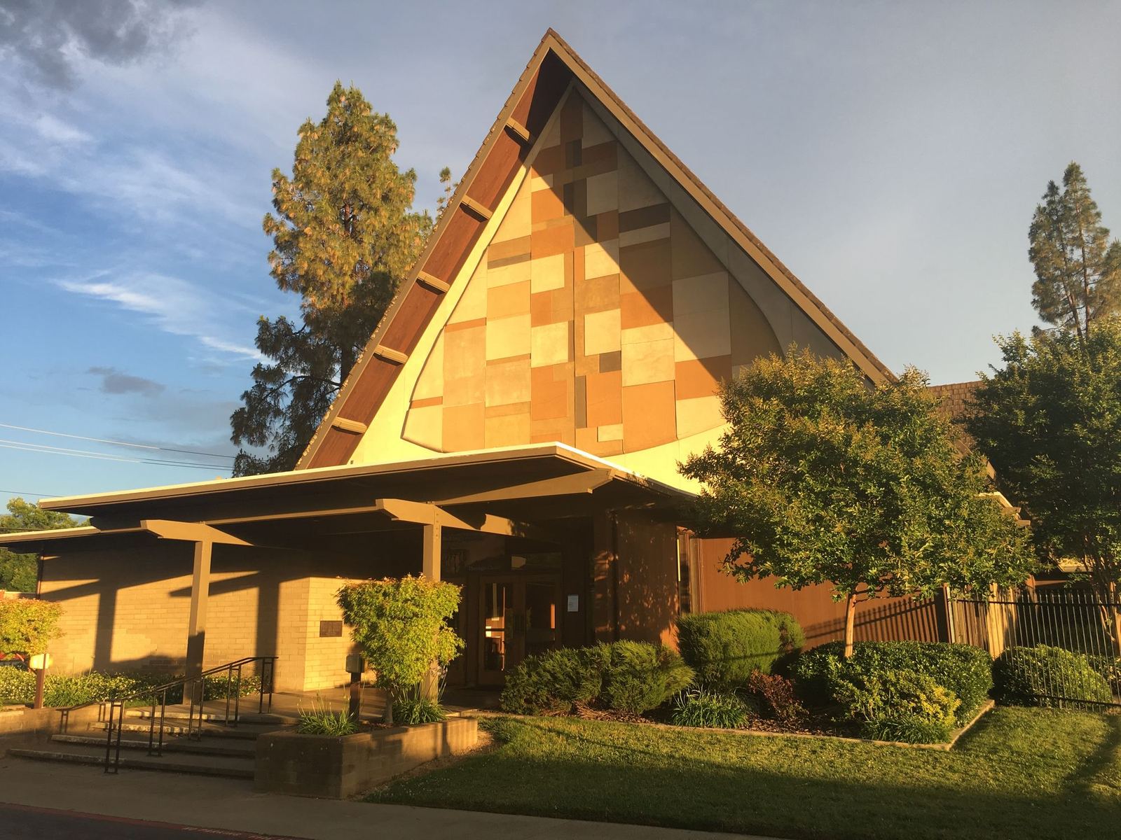 The church on Norris Avenue in late afternoon light, its steep A-frame roof rising above the entrance canopy